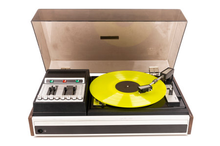 Vintage turntable record player with yellow vinyl isolated on white background.の写真素材