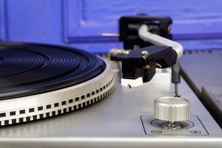 Close up of vintage turntable vinyl record player by blue wall.