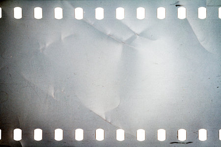Dusty and grungy 35mm film texture or surface. Perforated camera film isolated on white background.の写真素材