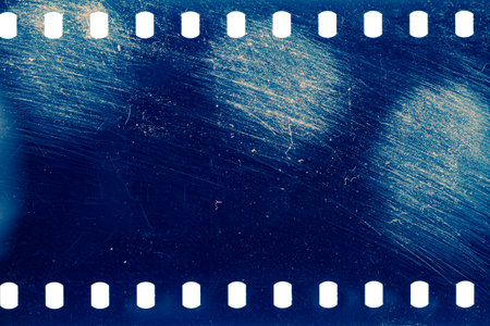 Dusty and grungy 35mm film texture or surface. Perforated scratched camera film isolated on white background.の写真素材