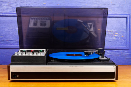 Vintage turntable vinyl record player with blue vinyl on a table