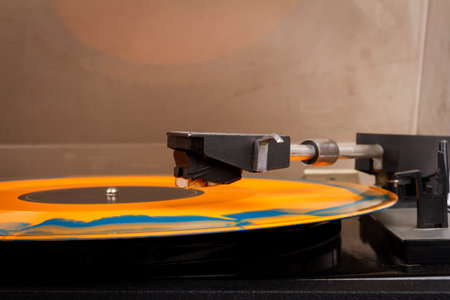 Close up of vintage turntable record player with orange and blue vinyl