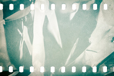 Dusty and grungy 35mm film texture or surface. Perforated scratched camera film isolated on white background.の写真素材