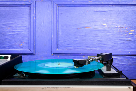 Vintage turntable vinyl record player with turquoise vinyl on a tableの写真素材