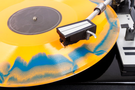 Close up of turntable needle on a vinyl record. Turntable playing vinyl. Needle on rotating orange and blue vinyl.の写真素材