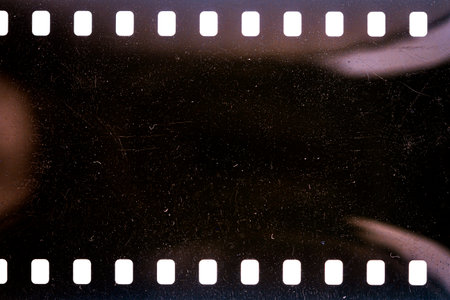 Dusty and grungy 35mm film texture or surface. Perforated scratched camera film isolated on white background.の写真素材
