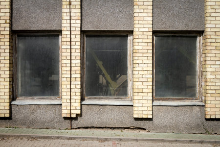Aged weathered yellow street wall with some windows