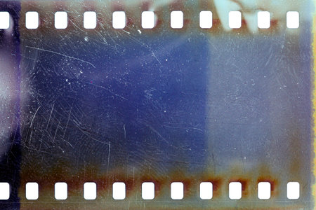 Dusty and grungy 35mm film texture or surface. Perforated scratched camera film isolated on white background.の写真素材