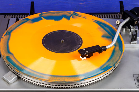 Close up of turntable needle on a vinyl record. Turntable playing vinyl. Needle on rotating orange and blue vinyl.の写真素材