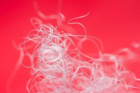 Extreme macro of polyester stable fiber on red background. Selective focus, shallow depth of field....