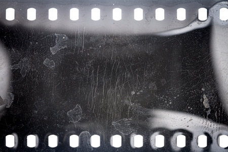 Dusty and grungy 35mm film texture or surface. Perforated scratched camera film isolated on white background.の写真素材