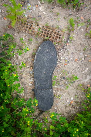 Old black rubber shoe sole lies on the ground. Ecology concept.の写真素材