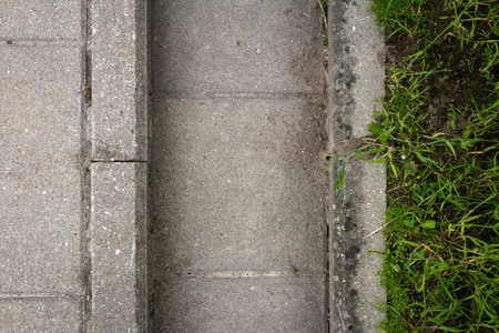 The system of drainage of melt water, rain streams and floods. Close up of concrete tiles and grass.