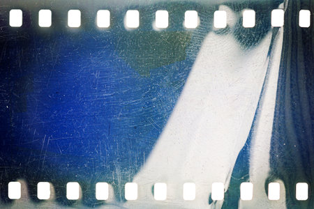 Dusty and grungy 35mm film texture or surface. Perforated scratched camera film isolated on white background.の写真素材