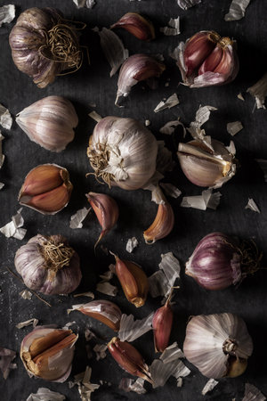 Fresh garlic bulbs and cloves grouped on black background. Flat lay. Top view. Food concept. Dark mood food photography.の写真素材