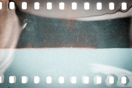 Dusty and grungy 35mm film texture or surface. Perforated scratched camera film isolated on white background.の写真素材