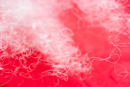 Extreme macro of polyester stable fiber on red background. Selective focus, shallow depth of field....