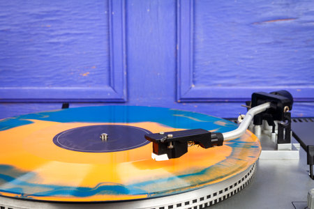Close up of turntable needle on a vinyl record. Turntable playing vinyl. Needle on rotating orange and blue vinyl.の写真素材