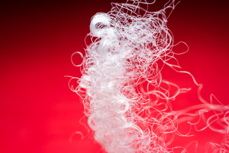 Extreme macro of polyester stable fiber on red background. Selective focus, shallow depth of field....