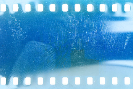 Dusty and grungy 35mm film texture or surface. Perforated scratched camera film isolated on white background.の写真素材