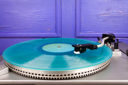 Close up of vintage turntable vinyl record player with turquoise vinyl