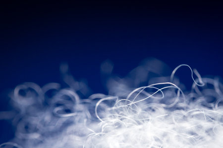 Extreme macro of polyester stable fiber on blue background. Selective focus, shallow depth of field....