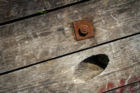 An old and cracked wooden panels with rusty nut and bolt in it as a backgroundの写真素材
