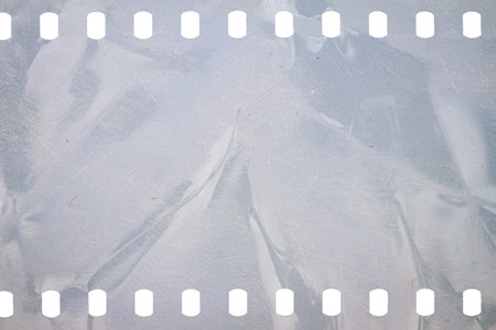 Dusty and grungy 35mm film texture or surface. Perforated scratched camera film isolated on white background.の写真素材