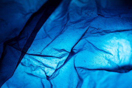 Extreme close up of blue empty plastic bag background. The plastic surface is wrinkly and tattered making abstract pattern. Selective focus, shallow depth of field.の写真素材