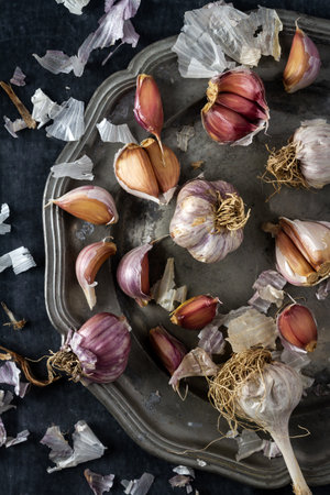 Raw garlic on grey pewter plate. Flat lay. Top view. Food concept. Dark mood food photography.の写真素材