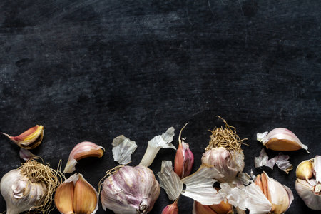 Fresh garlic bulbs and cloves grouped on black background. Flat lay. Top view. Food concept. Dark mood food photography.の写真素材