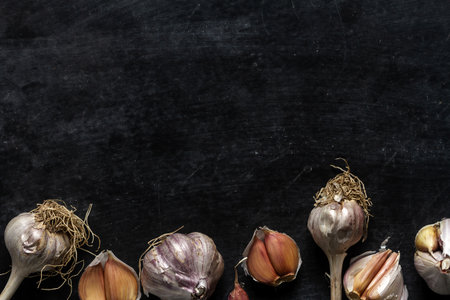 Fresh garlic bulbs and cloves grouped on black background. Flat lay. Top view. Food concept. Dark mood food photography.の写真素材