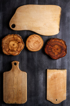 Old wooden cutting boards and tree trunk slices on black chalkboard background. Flat lay. Top view. Food concept.の写真素材