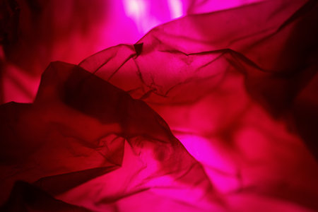 Extreme close up of red empty plastic bag background. The plastic surface is wrinkly and tattered making abstract pattern. Selective focus, shallow depth of field.の写真素材