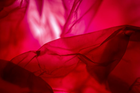Extreme close up of red empty plastic bag background. The plastic surface is wrinkly and tattered making abstract pattern. Selective focus, shallow depth of field.の写真素材