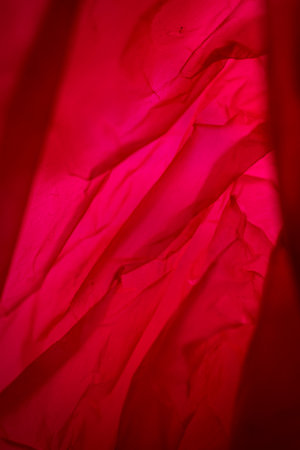 Extreme close up of red empty plastic bag background. The plastic surface is wrinkly and tattered making abstract pattern. Selective focus, shallow depth of field.の写真素材