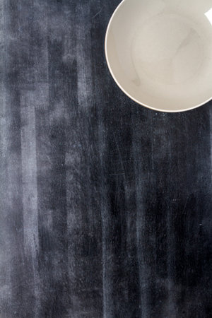 Top view of an empty gray plate placed on a black chalkboard background. Flat lay. Top view. Food...