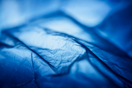 Extreme close up of blue empty plastic bag background. The plastic surface is wrinkly and tattered making abstract pattern. Selective focus, shallow depth of field.の写真素材
