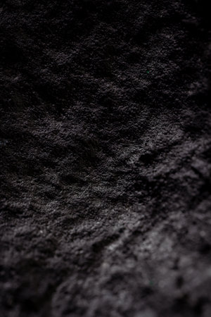 Extreme close up of painted in black handmade paper clay with a structure and rough texture. Selective focus, shallow depth of field.の写真素材