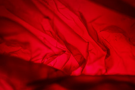 Extreme close up of red empty plastic bag background. The plastic surface is wrinkly and tattered making abstract pattern. Selective focus, shallow depth of field.の写真素材