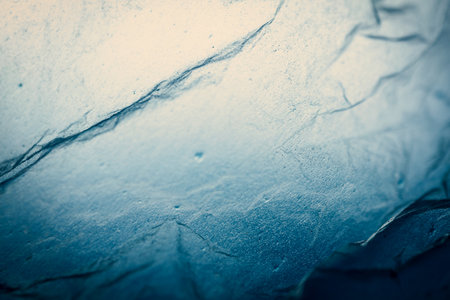 Extreme close up of blue empty plastic bag background. The plastic surface is wrinkly and tattered making abstract pattern. Selective focus, shallow depth of field.の写真素材
