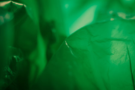 Extreme close up of green empty plastic bag background. The plastic surface is wrinkly and tattered making abstract pattern. Selective focus, shallow depth of field.の写真素材