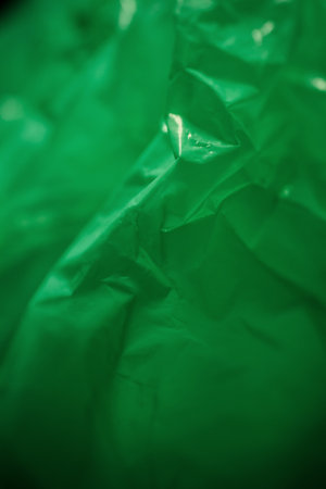 Extreme close up of green empty plastic bag background. The plastic surface is wrinkly and tattered making abstract pattern. Selective focus, shallow depth of field.の写真素材