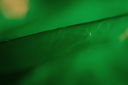 Extreme close up of green empty plastic bag background. The plastic surface is wrinkly and tattered...
