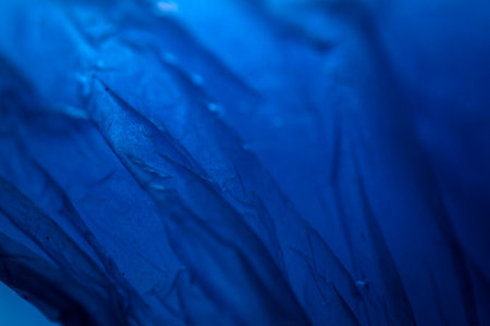 Extreme close up of blue empty plastic bag background. The plastic surface is wrinkly and tattered making abstract pattern. Selective focus, shallow depth of field.の写真素材