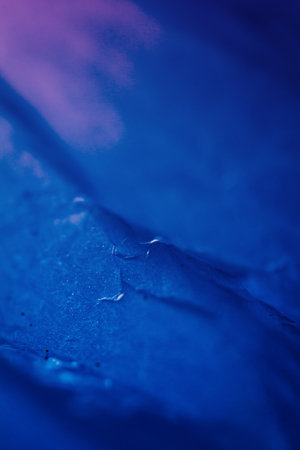 Extreme close up of blue empty plastic bag background. The plastic surface is wrinkly and tattered making abstract pattern. Selective focus, shallow depth of field.の写真素材