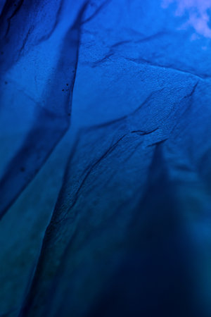 Extreme close up of blue empty plastic bag background. The plastic surface is wrinkly and tattered making abstract pattern. Selective focus, shallow depth of field.の写真素材
