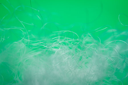 Extreme macro of polyester stable fiber on green background. Selective focus, shallow depth of field. Abstract dreamy backgroundの写真素材
