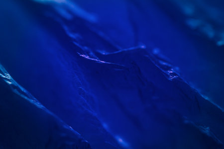 Extreme close up of blue empty plastic bag background. The plastic surface is wrinkly and tattered making abstract pattern. Selective focus, shallow depth of field.の写真素材