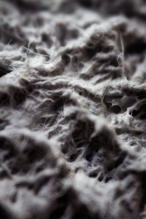 Extreme close up of old gray handmade paper clay with a structure and rough texture. Paper recycling. Selective soft focus, shallow depth of field.の写真素材